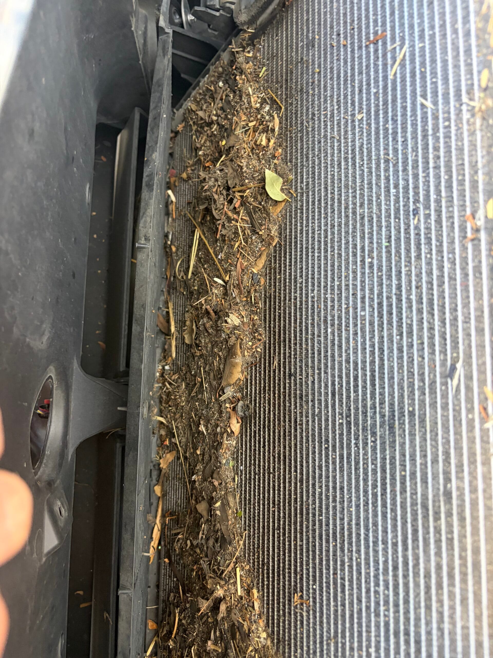 Close-up of debris and organic material packed between Tesla radiator fins